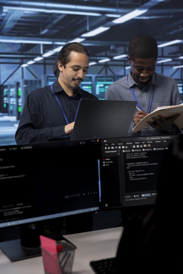 Happy engineers checking for signs of imminent failure in data center equipment. Upbeat colleagues discussing ways to prevent server clusters damages, monitoring critical systems